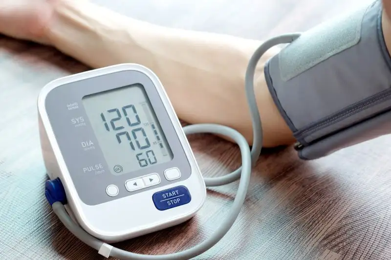 Ein Arm mit einer Blutdruckmanschette, die an ein digitales Messgerät angeschlossen ist