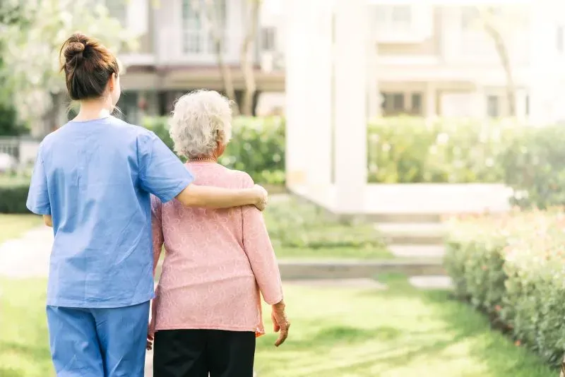 Pflegekraft stützt sanft eine ältere Frau