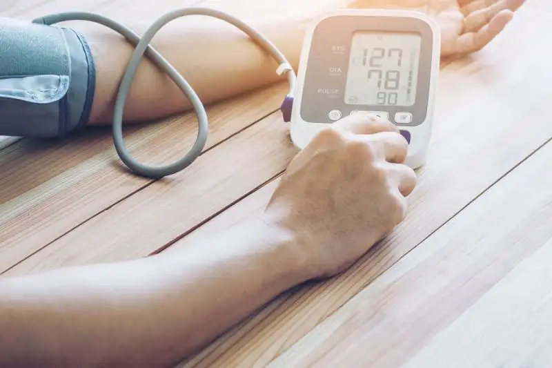 Ein Arm mit einer Blutdruckmanschette, die an ein digitales Messgerät angeschlossen ist