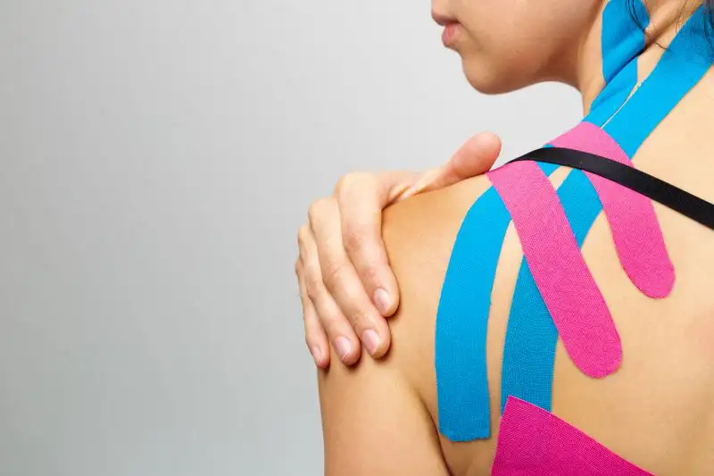 Eine Person mit blauem und rosa Kinesiologieband auf der Schulter