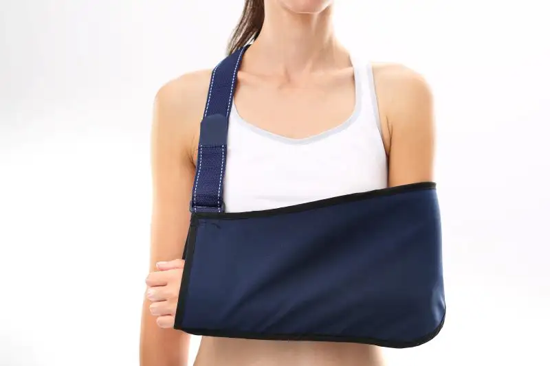 Eine Frau trägt eine marineblaue Armschlinge, die ihren rechten Arm stützt.