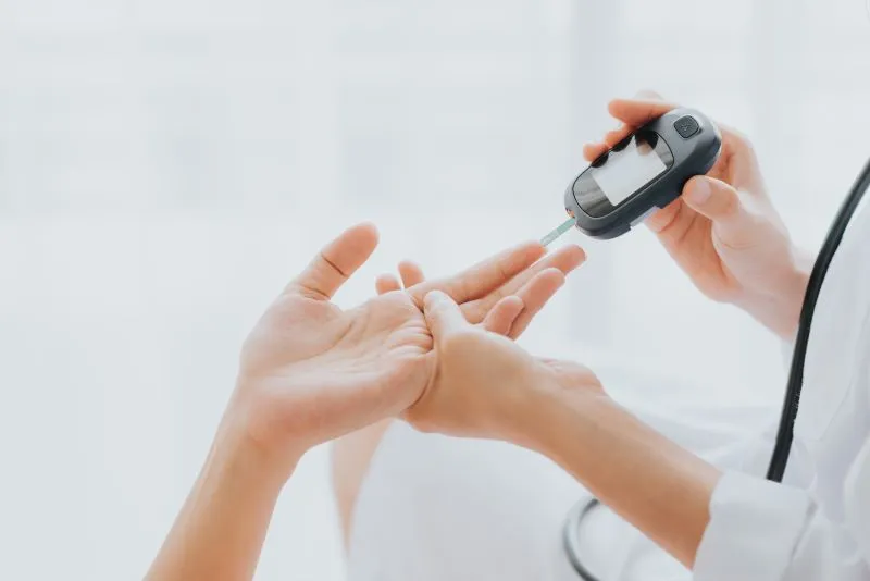 Eine medizinische Fachkraft prüft den Blutzucker mit einem Glucometer an der Fingerspitze eines Patienten