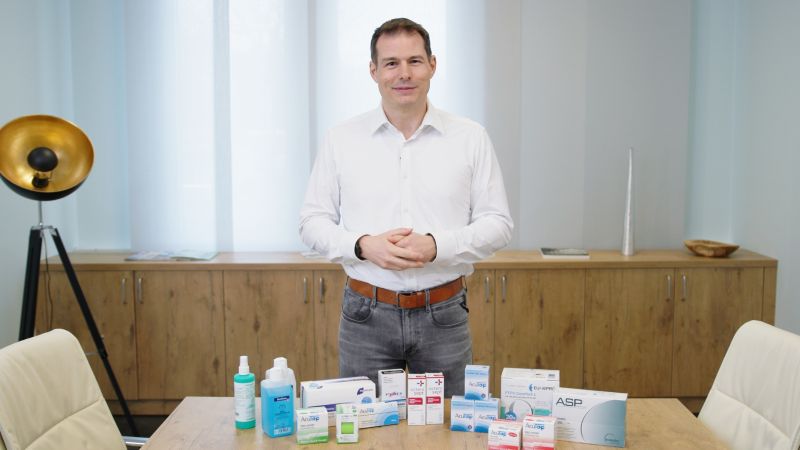Ein Mann steht vor einem Tisch, der mit verschiedenen Medizinprodukten gefüllt ist.