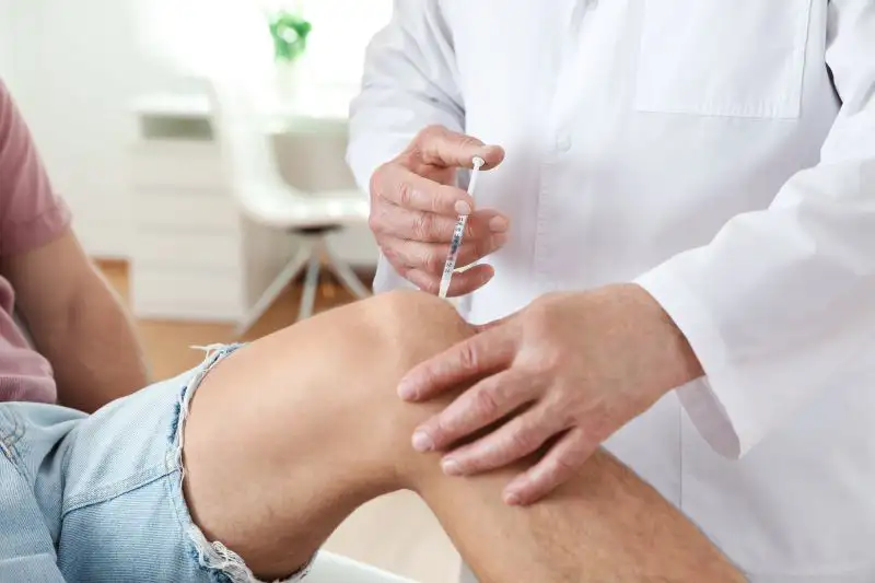 Ein Arzt verabreicht einem Patienten eine Injektion in das Knie
